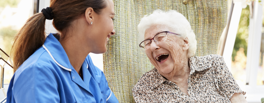 Life Assure Senior Woman Sitting In Chair And Laughing With Caregiver Nurse Hero